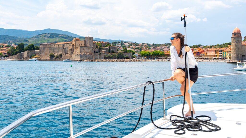 Eine Frau genießt eine Bootstour vor einer historischen Küstenstadt.