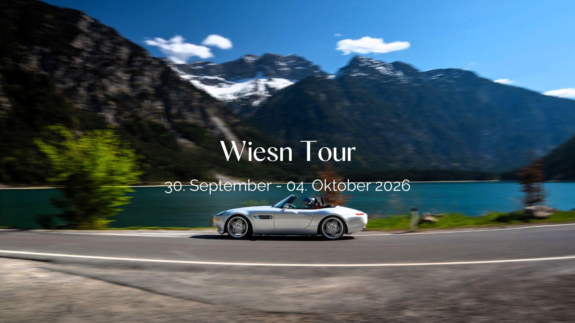 Header Bild der Wiesn Tour: BMW Z8 Cabrio fährt auf Alpenstraße entlang eines türkisen Bergsees.