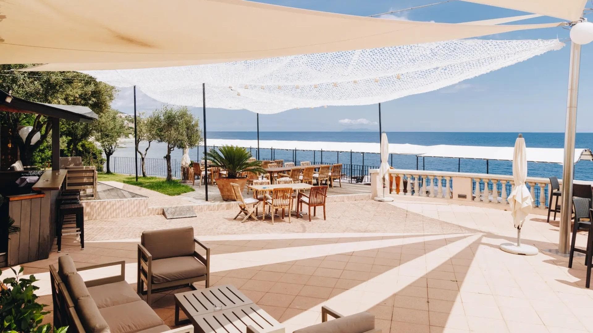 Elegante Terrasse mit Meerblick, stilvollen Möbeln und sanfter Sonneneinstrahlung in luxuriösem Ambiente.