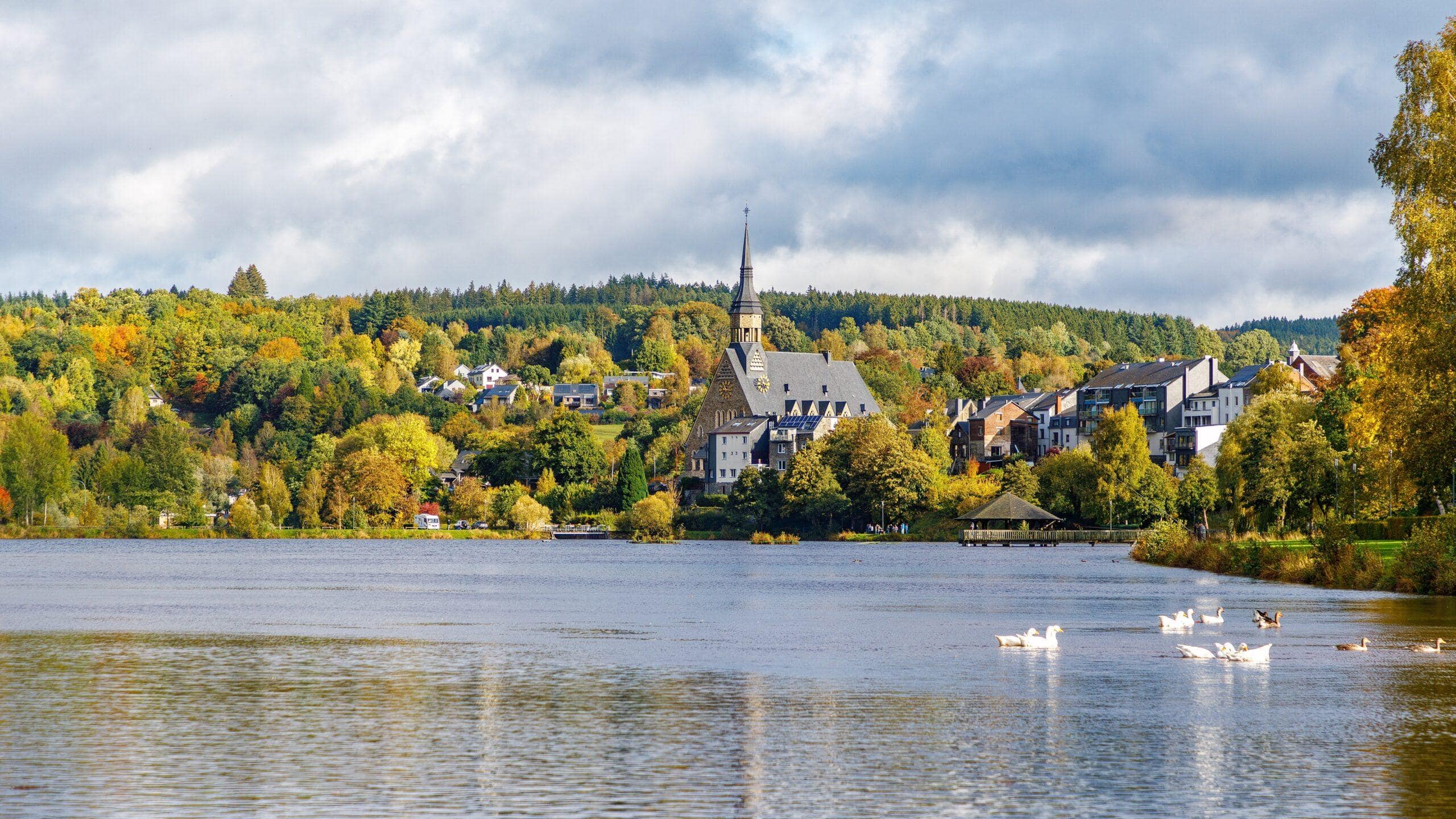 Ardennen Tour: Landschaft mit Kirche am See (Vielsalm) und bunten Herbstbäumen.