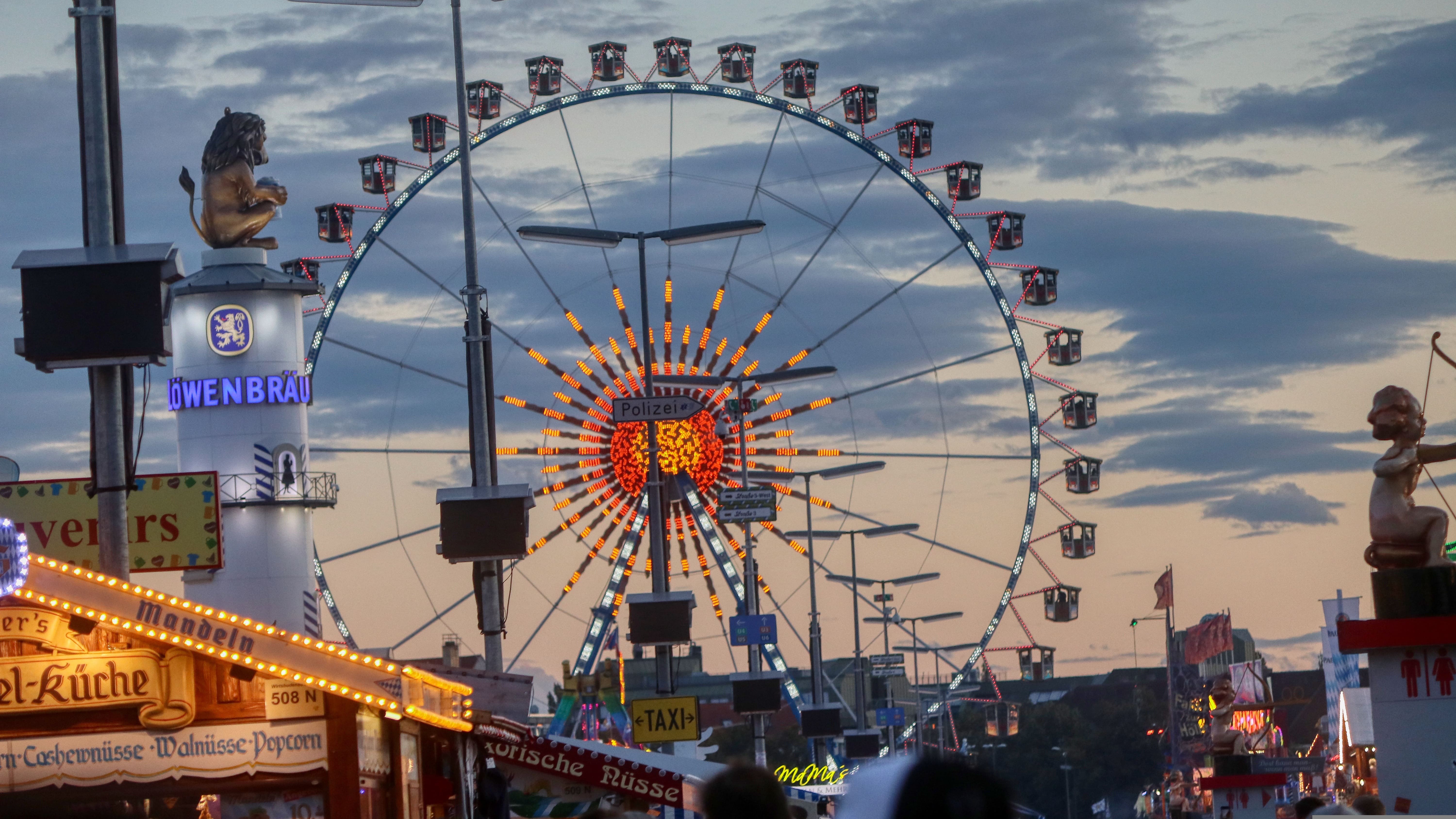 Stimmungsvolle Abenddämmerung auf dem Oktoberfest mit Riesenrad und Löwenbräu Turm.